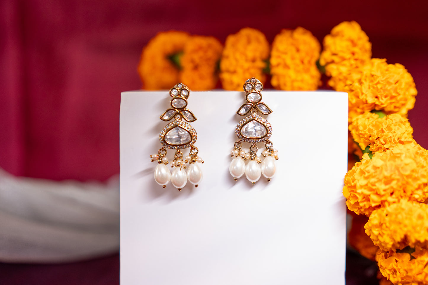 Chandelier earrings with stone polkis and dual sized pearls in a gold finish