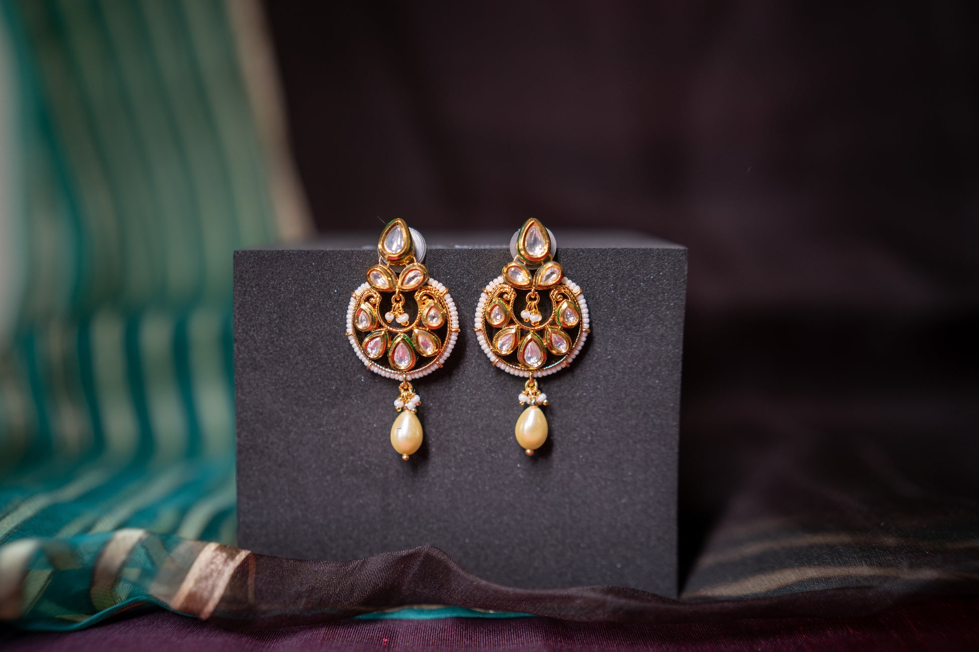 Our beautiful rendition of a chandbali features gold finish and stone polkis set in the Indian tradition of perfection but we also add a softness to the earrings by letting a pearl gently hang at the end of the earrings to give it an exquisite look