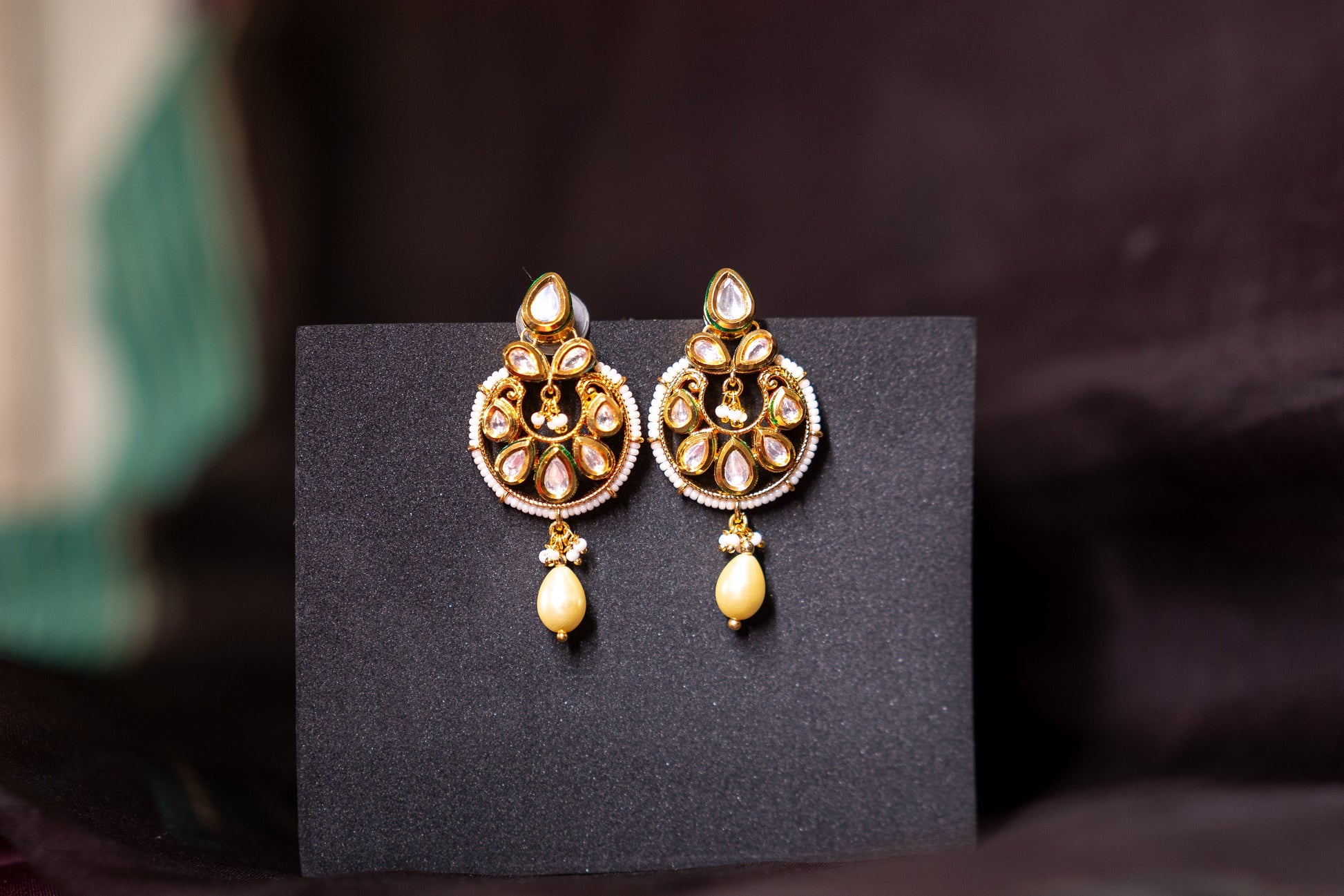 Our beautiful rendition of a chandbali features gold finish and stone polkis set in the Indian tradition of perfection but we also add a softness to the earrings by letting a pearl gently hang at the end of the earrings to give it an exquisite look