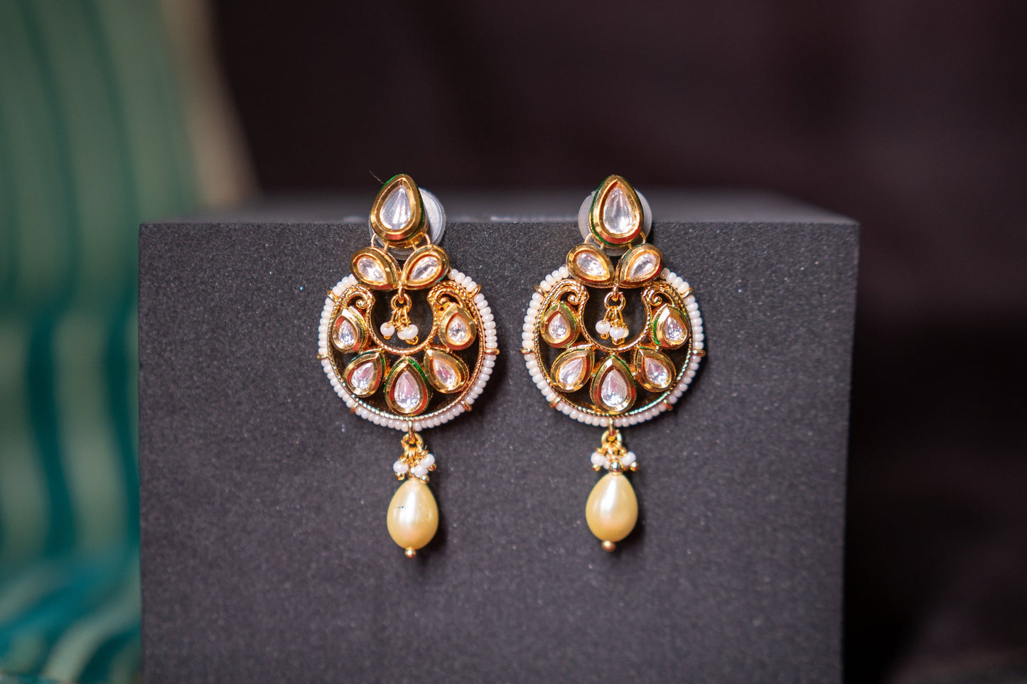 Our beautiful rendition of a chandbali features gold finish and stone polkis set in the Indian tradition of perfection but we also add a softness to the earrings by letting a pearl gently hang at the end of the earrings to give it an exquisite look